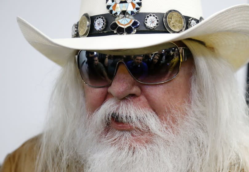 FILE - In this Jan. 29, 2013, file photo, reporters are reflected in the sunglasses of Leon Russell as he answers a question at a news conference in Tulsa, Okla. Russell, who sang, wrote and produced some of rock 'n' roll's top records, has died. (AP Photo/Sue Ogrocki, File)