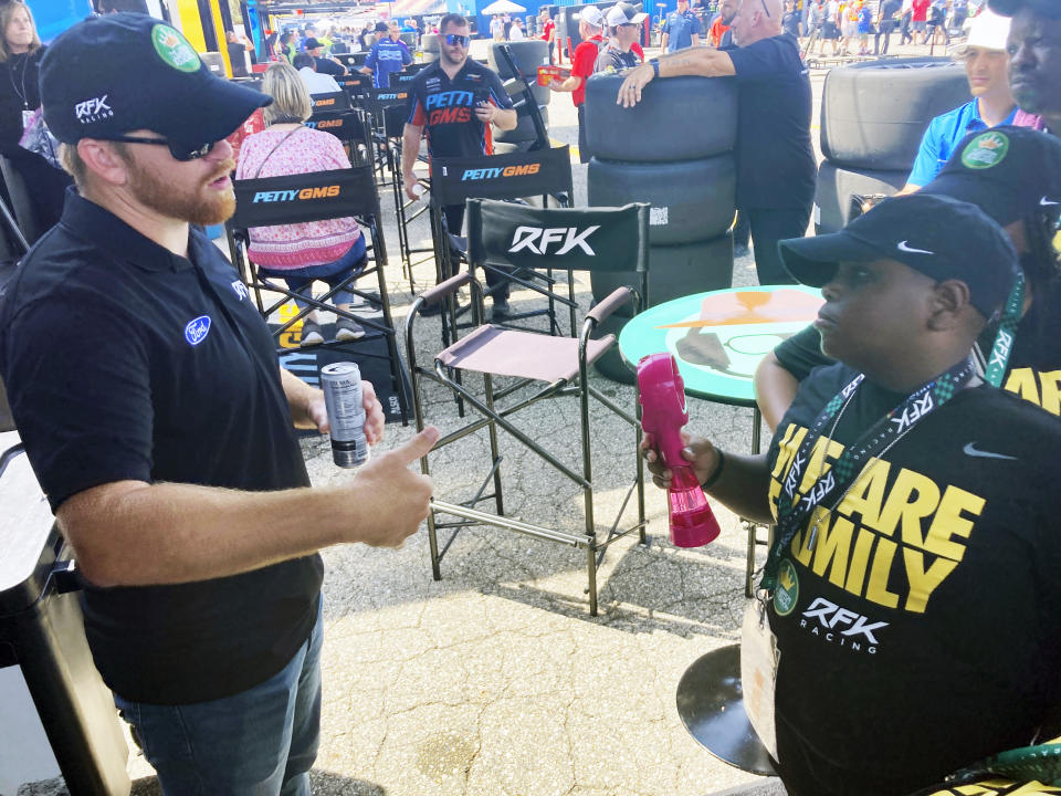 James Bromsey III,right, a sixth-grader at LeBron James' I Promise School in Akron, Ohio, talks with NASCAR driver Chris Buescher, Sunday, Aug. 7, 2022 in Brooklyn, Mich. Bromsey was given an all-access tour of Michigan International Speedway in Brooklyn, Mich., on Sunday. Chris Buescher’s No. 17 Ford had a paint job that highlighted the LeBron James Family Foundation. (AP Photo/Larry Lage)