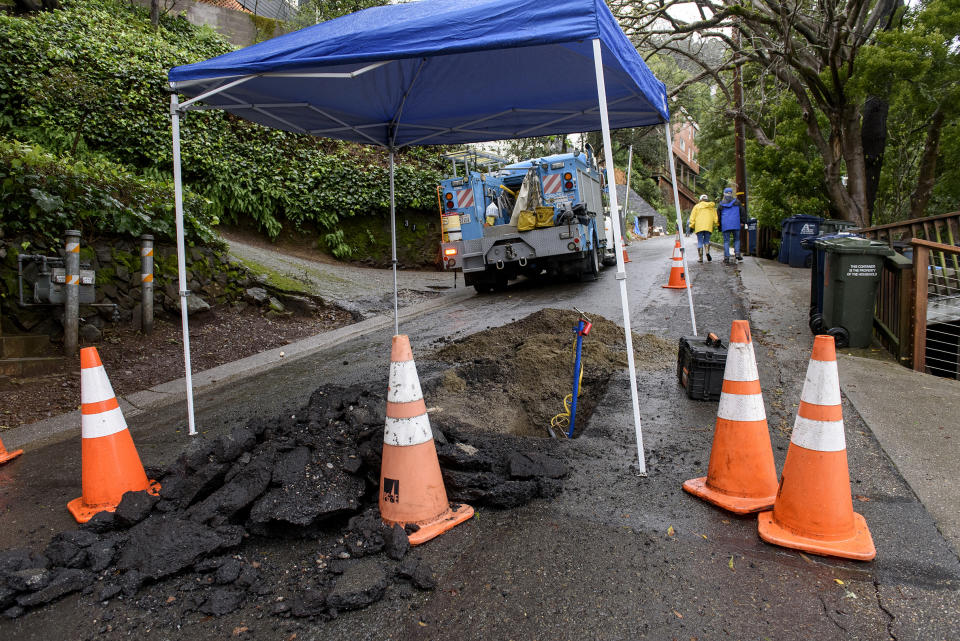 A Pacific Gas and Electric truck is parked in front of street damage in the aftermath of a mudslide that destroyed three homes on a hillside in Sausalito, Calif., Thursday, Feb. 14, 2019. Waves of heavy rain pounded California on Thursday, filling normally dry creeks and rivers with muddy torrents, flooding roadways and forcing residents to flee their homes in communities scorched by wildfires. (AP Photo/Michael Short)