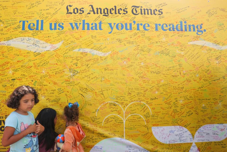 Mary Lara, center, signs what book she is reading alongside her daughter Aria Cook, 4, and Selena Cook, 8.