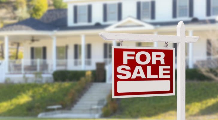 a large house has a For Sale sign out front