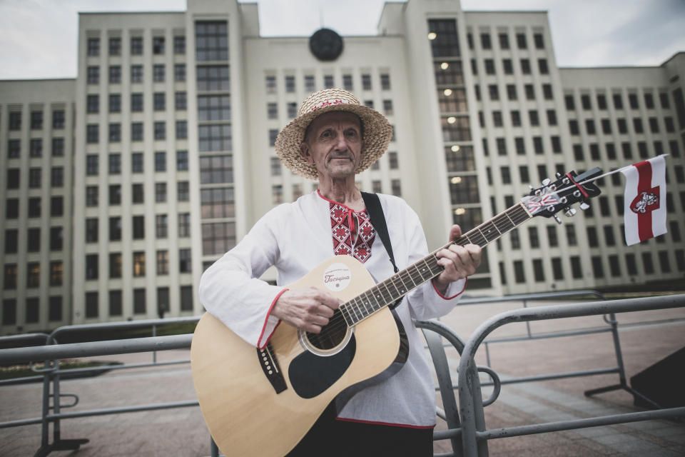 Ales Varhamiev, 62, a pensioner and singer plays a guitar as he poses for a photo during an opposition rally in Independence Square in Minsk, Belarus, Thursday, Aug. 20, 2020. Varhamiev brought his guitar to play the protesters' anti-Lukashenko anthem "Cockroach, Get Out!" (AP Photo/Evgeniy Maloletka)