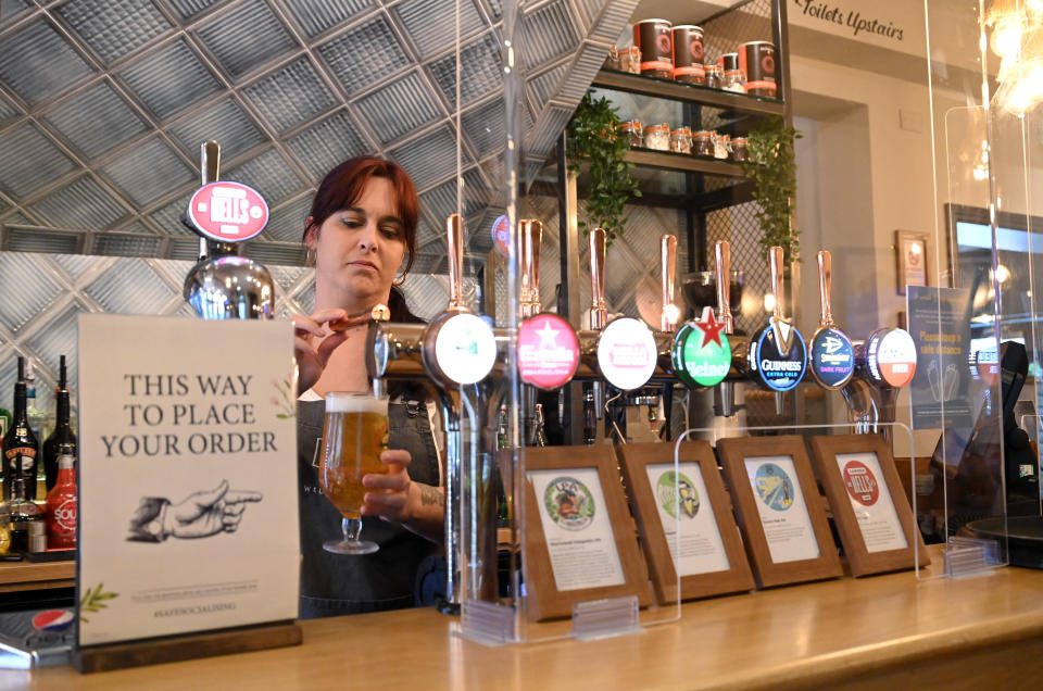 A staff member at the Wellington Pub pours drinks behind a protective screen on July 4 in Borehamwood, England. (Photo: Karwai Tang via Getty Images)