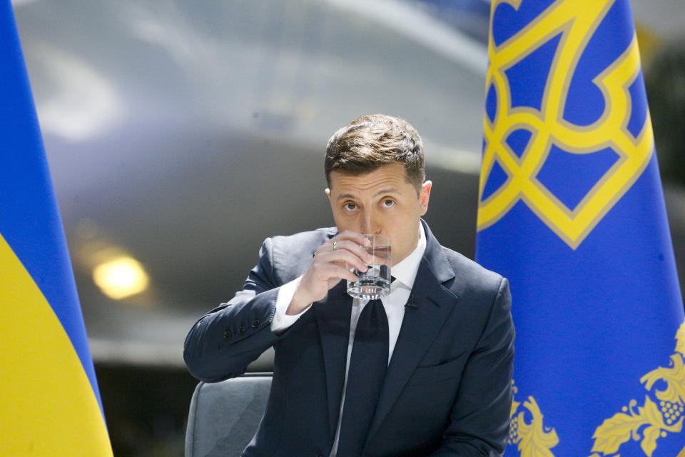 Ukrainian President Volodymyr Zelenskyy drinks water while speaking to the media during a news conference with the world's largest airplane, Ukrainian Antonov An-225 Mriya in the background at the Antonov aircraft factory in Kyiv, Ukraine, Thursday, May 20, 2021. (AP Photo/Efrem Lukatsky)