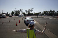 A volunteer controls traffic at a city-run, drive-thru COVID-19 testing site in South Central Los Angeles, Friday, May 22, 2020. While most of California is welcoming a slight return toward normal this holiday weekend, Los Angeles will not be joining the party. The nation's largest county is not planning to reopen more widely until the next summer holiday, July 4th, because of a disproportionately large share of the state's coronavirus cases and deaths that have hampered the county's ability to rebound and meet strict criteria to get more people back to work. (AP Photo/Jae C. Hong)