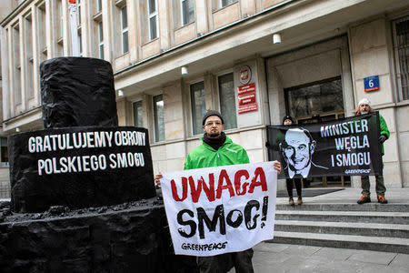 Greenpeace activists demonstrate on the street following the decision of the Court of Justice of the European Union (CJEU), after they handed a big, carbon cake to Poland's Energy Mister Krzysztof Tchorzewski as a symbol of 'protecting Polish smog', in Warsaw, Poland February 22, 2018. The banners read: (R) 'Minister of carbon and smog", (C) "Attention smog!". Agencja Gazeta/Dawid Zuchowicz via REUTERS