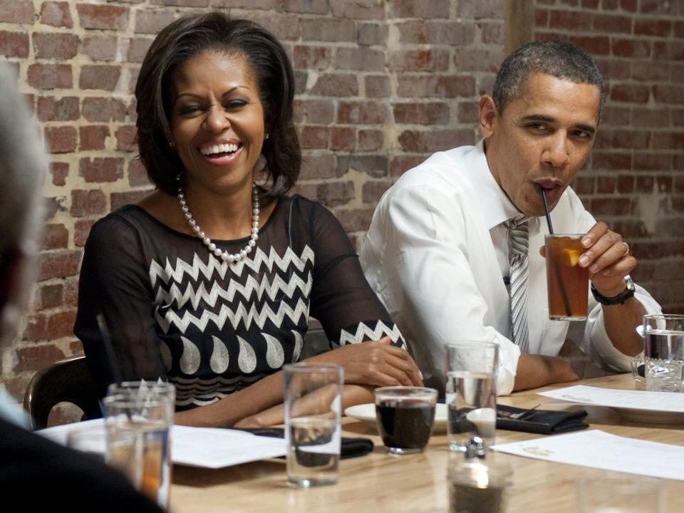 Michelle and Barack Obama at dinner. Michelle wears a black and white dress.