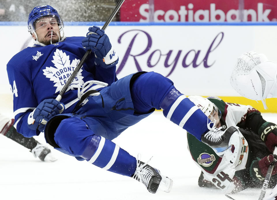 Toronto Maple Leafs' Auston Matthews, left, tumbles after a collision during second-period NHL hockey game action against the Arizona Coyotes in Toronto, Thursday, Feb. 29, 2024. (Chris Young/The Canadian Press via AP)