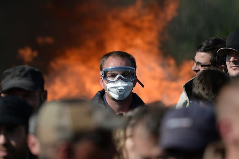 Striking workers are evacuated by riot police as they block the access to an oil depot near the Total refinery of Donges, western France, on May 27, 2016