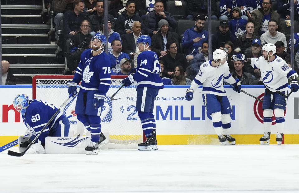 Tampa Bay Lightning's Brayden Point (21) celebrates his goal against Toronto Maple Leafs' goaltender Joseph Woll (60) with Nikita Kucherov (86) during the second period of an NHL hockey game Wednesday, April 3, 2024, in Toronto. (Chris Young/The Canadian Press via AP)