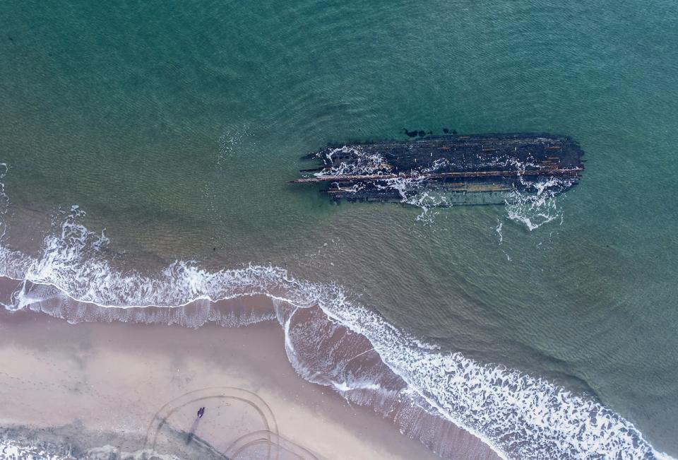 The massive, overturned hull of a seemingly ancient ship has appeared without warning along Newfoundland's southwestern tip as shown in this handout image provided by Corey Purchase. Wanda Blackmore says her 21-year-old son, Gordon, came roaring into her house last Saturday morning after spotting the long shadow beneath the water just off the beach in Cape Ray, N.L. 