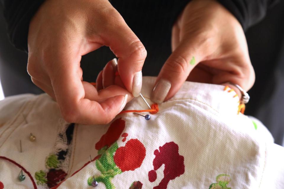 Betsy Flores of Other Lives Studio embroiders a pair of pants.