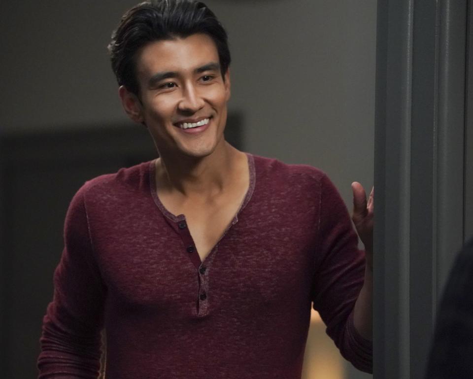 actor alex landi as dr nico kim in season 17 of grey's anatomy, shown in wearing a burgundy shirt and smiling at someone off camera