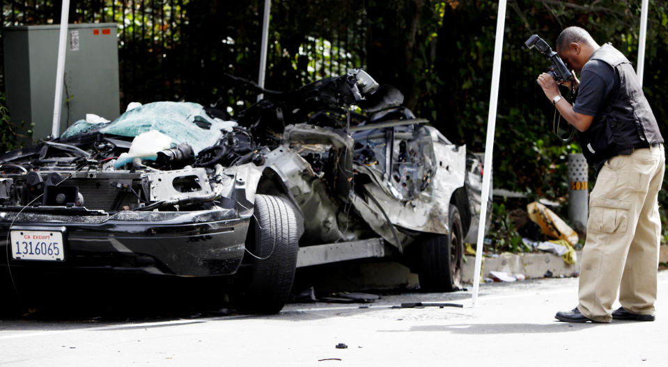 Los Angeles Police Department photographer Norm Thomas photographs the crushed police car, Friday, March 7, 2014 in Beverly Hills, Calif. A veteran Los Angeles police officer was killed and his rookie partner was critically injured Friday when their patrol car collided with a big rig on a residential street. The truck driver also was injured. (AP Photo/Los Angeles Times, Francine Orr, Pool)