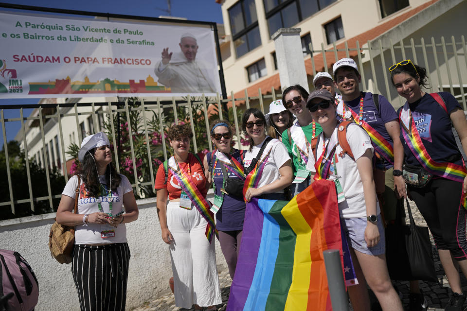 Victoria, left, from Spain, stands with representatives of Dignity USA, a group of LGBTQ+ Catholics, outside the Sao Vicente de Paulo Parish Social Center, after Pope Francis visited it, in the Serafina neighbourhood of Lisbon, Friday, Aug. 4, 2023. In Lisbon, Francis has emphasized the inclusive message of the church that he has championed throughout his 10-year papacy, telling the World Youth Day opening ceremony that "in the church, there is room for everyone" and leading the crowd of a half-million people in a chant of "everyone, everyone, everyone." That message has resonated in particular with LGBTQ+ Catholics, who have long felt ostracized by a church that considers homosexual activity "intrinsically disordered." (AP Photo/Armando Franca)