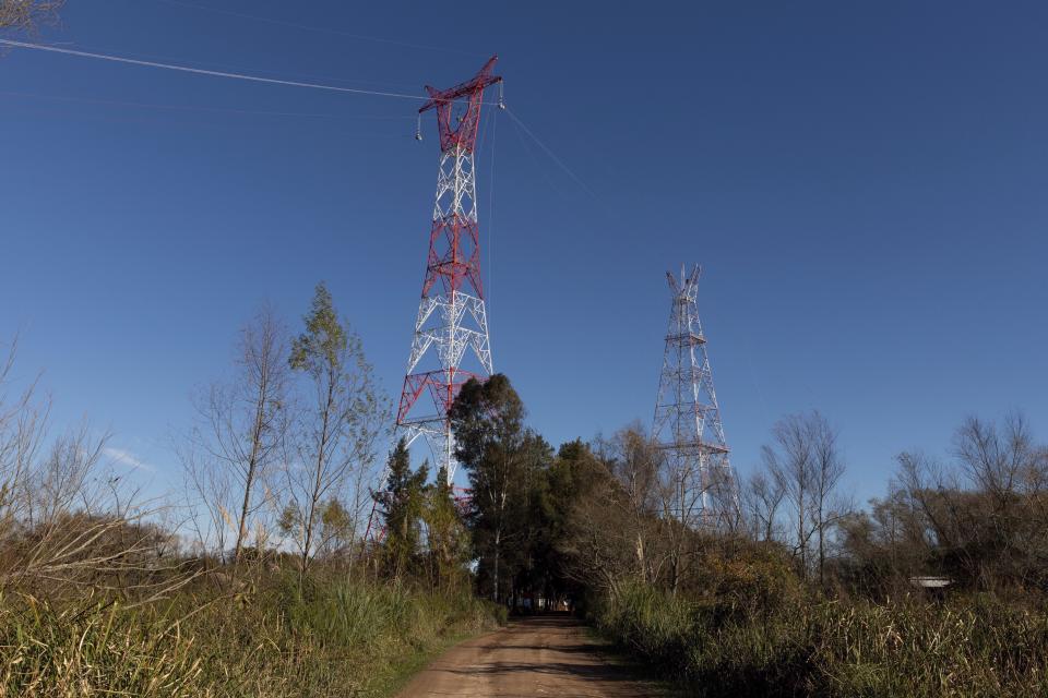 Technicians work to dismantle Tower 412, far right, and replace it with a new one, left, in the Litoral corredor near the town of Zarate, on the border of Buenos Aires and Entre Rios provinces, Argentina, Wednesday, June 19, 2019. Located in the Parana River, Tower 412 hasn't been operational since April while workers built its replacement tower, and a bypass system had been set up to handle the current. Argentina's government suggested the origin of Sunday's blackout may stem from this corredor, and hopes to give a detailed explanation of events in twelve days time once all the technical elements have been analyzed. (AP Photo/Tomas F. Cuesta)