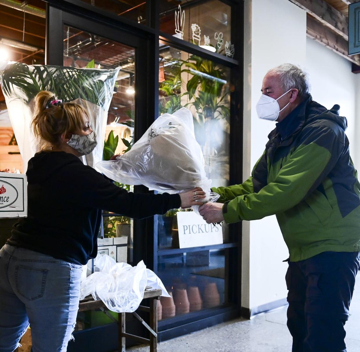 A florist hands a curbside order to a customer during the Valentine's Day rush in Almonte, Ont., in February 2021. THE CANADIAN PRESS/Sean Kilpatrick