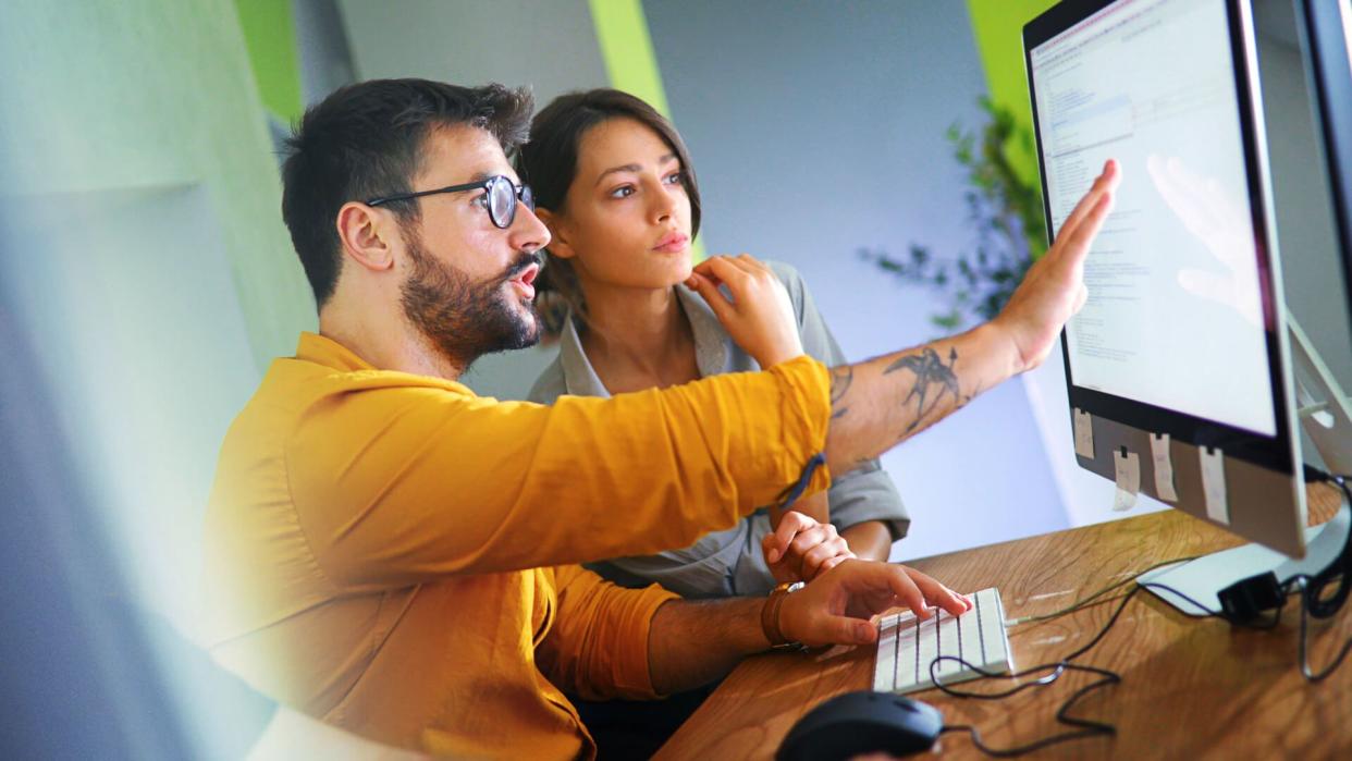 Closeup side view of couple of mid 20's software developers resolving some issues with the code they're currently working on.