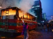 A Bangladeshi youth sprays water on a burning bus as he and others try to extinguish the fire in Dhaka on January 2, 2014