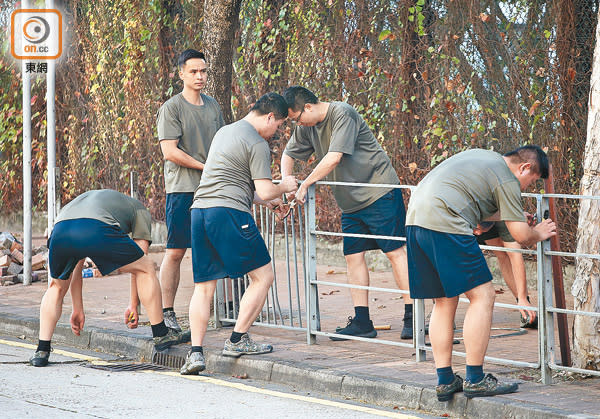 駐港解放軍合力把被暴徒拆毀的欄杆，重新裝上行人路。（李華輝攝）