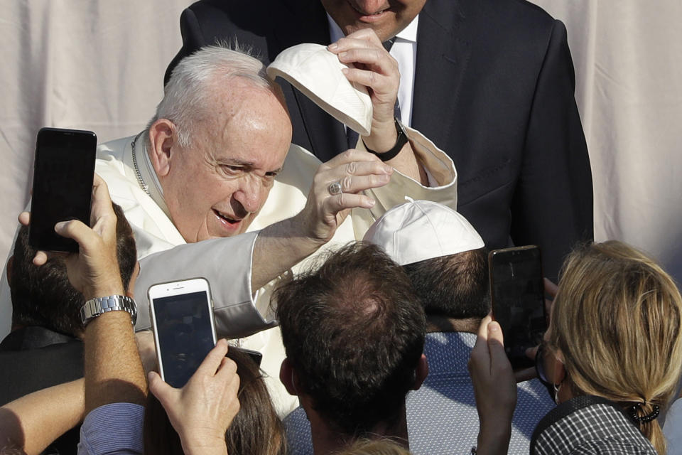 Pope Francis exchanges a skull cap which was donated by faithful as he arrives in the St. Damaso courtyard on the occasion of his weekly general audience at the Vatican, Wednesday, Sept. 16, 2020. (AP Photo/Gregorio Borgia)