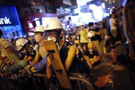 Pro-democracy protesters stand by a barricade as they prepare for a confrontation with riot police at the Mongkok shopping district of Hong Kong October 19, 2014. REUTERS/Carlos Barria