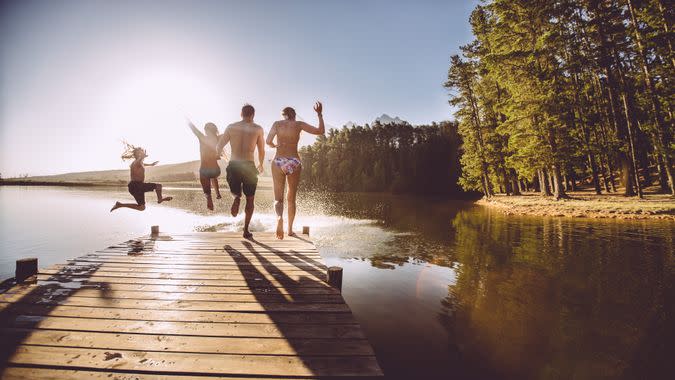 A group of people jumping into the water from a jetty or dock.