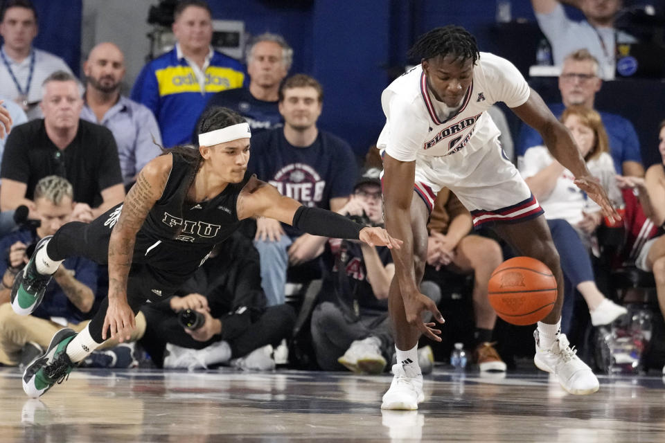 Florida International guard Javaunte Hawkins (3) and Florida Atlantic forward Brenen Lorient (0) go after a loose ball during the first half of an NCAA college basketball game, Wednesday, Dec. 13, 2023, in Boca Raton, Fla. (AP Photo/Marta Lavandier)