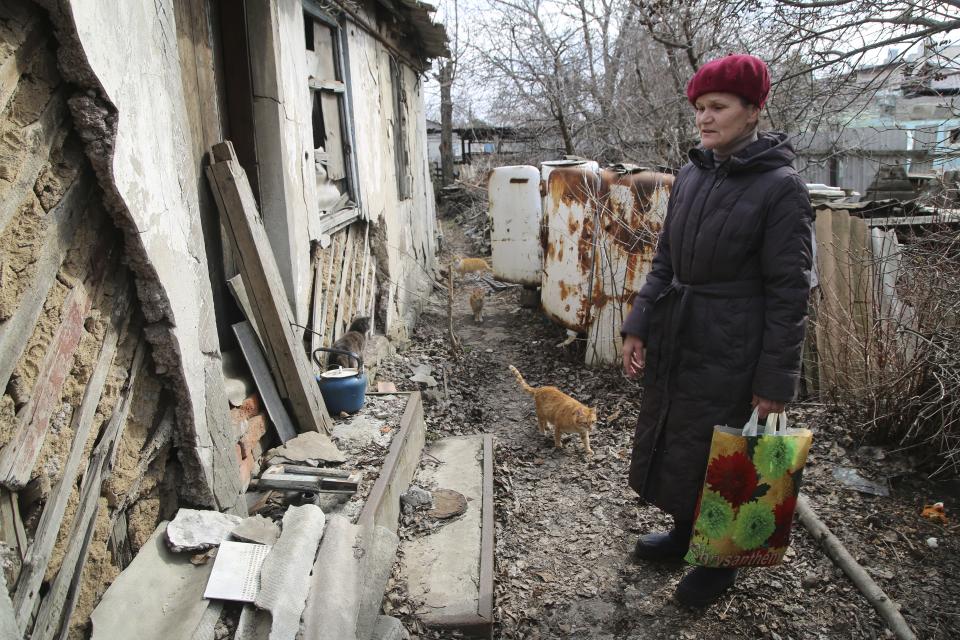 A woman visits her home in the separatist-controlled territory to collect her belongings after a recent shelling near a frontline outside Donetsk, eastern Ukraine, Friday, April 9, 2021. Tensions have built up in recent weeks in the area of the separatist conflict in eastern Ukraine, with violations of a cease-fire becoming increasingly frequent. (AP Photo)