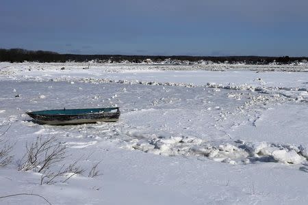 A boat sits in a snow and ice covered salt marsh near Wingaersheek Beach in Gloucester, Massachusetts February 20, 2015. REUTERS/Brian Snyder