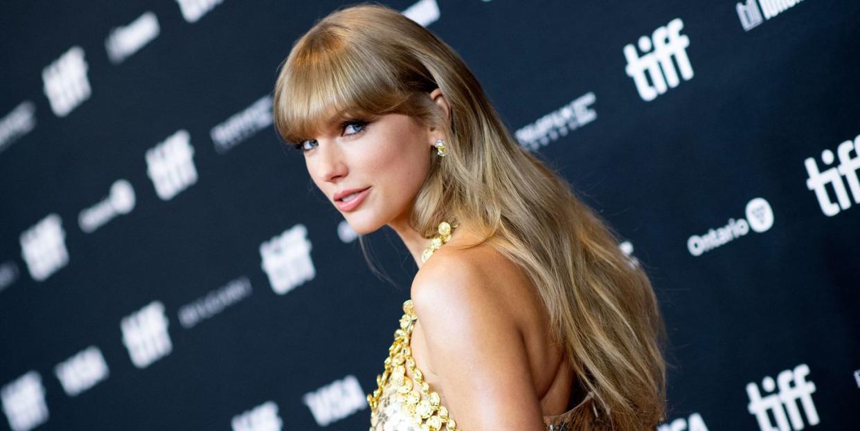 taylor swift looking over shoulder on red carpet in gold dress