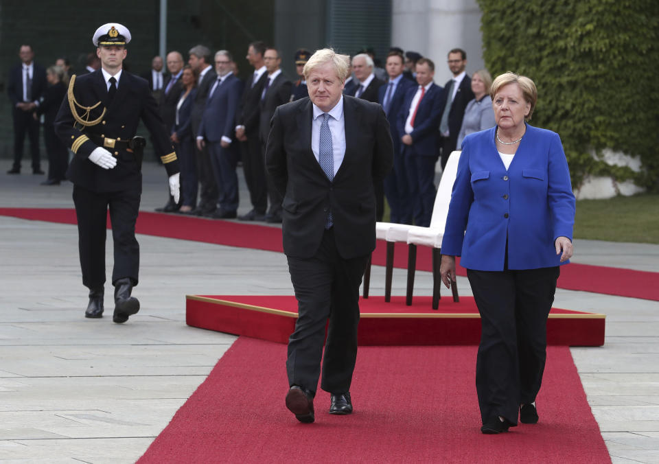 German Chancellor Angela Merkel welcomes Britain's Prime Minister Boris Johnson with military honors for a meeting at the Chancellery in Berlin, Germany, Wednesday, Aug. 21, 2019. (AP Photo/Michael Sohn)