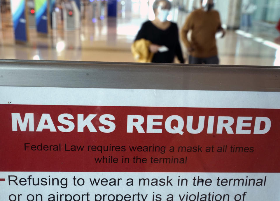 To prevent the spread of Covid-19, a sign directs travelers to wear masks at Love Field Tuesday, March 2, 2021, in Dallas. (AP Photo/LM Otero)