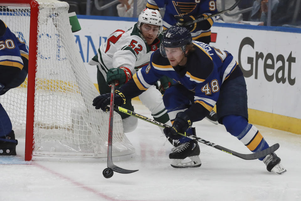St. Louis Blues' Scott Perunovich (48) and Minnesota Wild's Connor Dewar (52) vie for the puck during the third period in Game 6 of an NHL hockey Stanley Cup first-round playoff series Thursday, May 12, 2022, in St. Louis. (AP Photo/Michael Thomas)