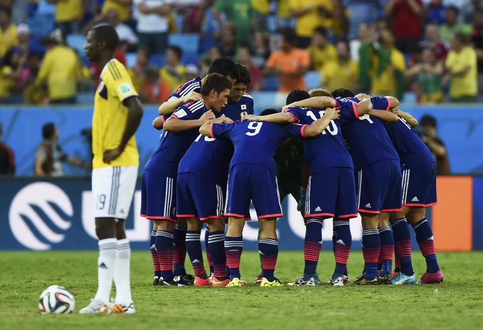 Japan's team huddle near Colombia's Adrian Ramos before the second half kickoff during their 2014 World Cup Group C soccer match at the Pantanal arena in Cuiaba June 24, 2014. REUTERS/Dylan Martinez (BRAZIL - Tags: SOCCER SPORT WORLD CUP)