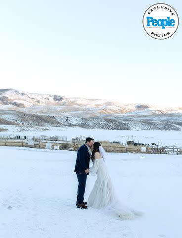 <p>markandjenna.pic-time.com</p> Ian Flanigan and wife Kelsey kiss in the snow on their wedding day