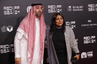 Red Sea International Film Festival Chairman Mohammed Al-Turki, left, and Saudi filmmaker Haifa al-Mansour pose for photographers on the red carpet during the opening of the first edition of the festival, in Jiddah, Saudi Arabia, late Monday, Dec. 6, 2021. Saudi Arabia is holding its first ever film festival three and-a-half years after the first movie premiered in cinemas in the kingdom. The festival featured a red carpet with women in floor-length ball gowns, a stark departure from past years when females had to wear the long flowing robe known as the abaya in public. (AP Photo/Amr Nabil)