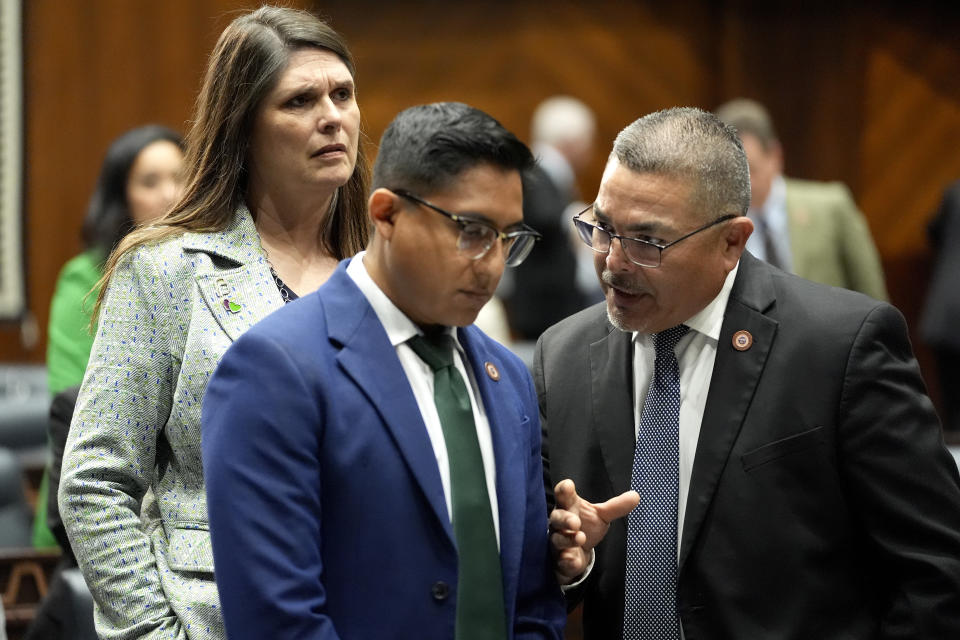 Arizona State Rep. Lupe Contreras, D, right, speaks with Rep. Oscar De Los Santos, D, as Stephanie Stahl Hamilton, D, looks on on the House floor, Wednesday, April 17, 2024, at the Capitol in Phoenix. House Republicans have again blocked an effort for the chamber to take up legislation that would repeal Arizona’s near-total ban on abortions. (AP Photo/Matt York)