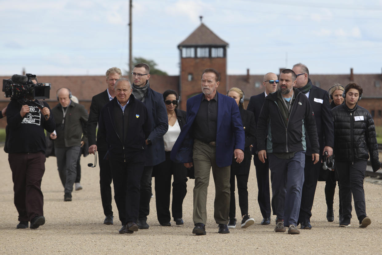 Arnold Schwarzenegger, center, and Simon Bergson, chairman of The Auschwitz Jewish Center Foundation, third left, visit Auschwitz - Birkenau Nazi German death camp in Oswiecim, Poland, Wednesday, Sept. 28, 2022. Film icon Arnold Schwarzenegger visited the site of the Nazi German death camp Auschwitz on Wednesday to send a message against hatred. The "Terminator" actor was given a tour of the site, viewing the barracks watchtowers and the remains of gas chambers that endure as evidence of the German extermination of Jews, Roma and others during World War II. (AP Photo/Michal Dyjuk)