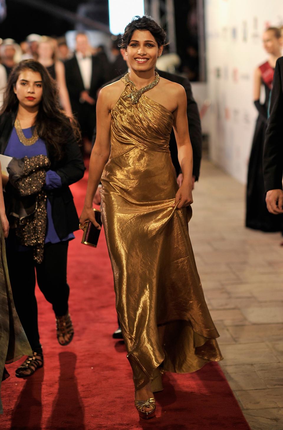 Earlier in the week, Freida Pinto glittered down the red carpet in this gorgeous gold gown by Ralph Lauren, complete with a serpent for a collar. She complemented her gown with a Ferragamo clutch, gold heels by Charlotte Olympia and breathtaking makeup.