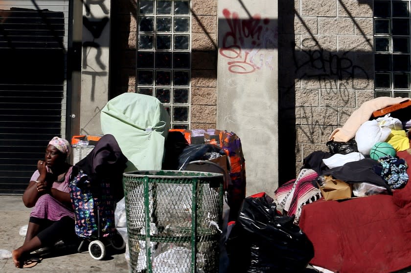 LOS ANGELES, CA - AUG. 11, 2020. A woman sits beside her belongings on thhe sidewalk along Sixth Street in Los Angeles on Tuesday, Aug. 11, 2020. Many downtown stores and eateries remain shuttered or restricted because of coronavirus. Leases and rents are spiraling downward, and large numbers of hhomeless people live on the streets. (Luis Sinco/Los Angeles Times)