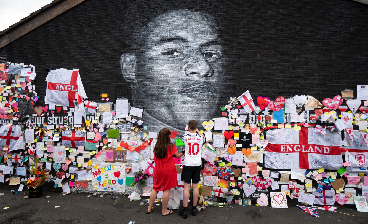 Mackenzie Robertson and his mother Sally Coles-Robertson put up a message on the mural of Manchester United striker and England player Marcus Rashford on the wall of the Coffee House Cafe on Copson Street, Withington. The mural appeared vandalised on Monday after the England football team lost the UEFA Euro 2021 final. Picture date: Tuesday July 13, 2021. Photo credit should read: Danny Lawson/PA Wire