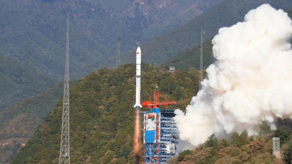 a small white rocket lifts off from forested mountain terrain.