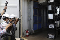 Journalists take photos of some of the processors used for bitcoin calculations inside a container at the La Geo Geothermal Power Plant in Berlin municipality, Usulutan department, El Salvador, Friday, Oct. 15, 2021. The government announced that it has installed 300 processors at this plant to "mine" cryptocurrency, and is using geothermal resources from the country’s volcanos to run the computers that perform the calculations to verify transactions in bitcoin, recently made legal tender. (AP Photo/Salvador Melendez)