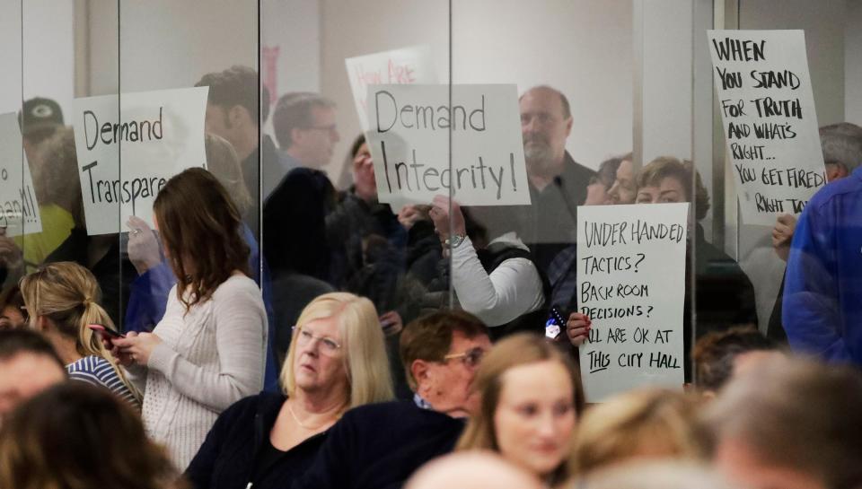 People hold signs of support for Todd Wolf during a meeting at which Wolf was terminated at Sheboygan City Hall, Monday, January 9, 2022, in Sheboygan, Wis.