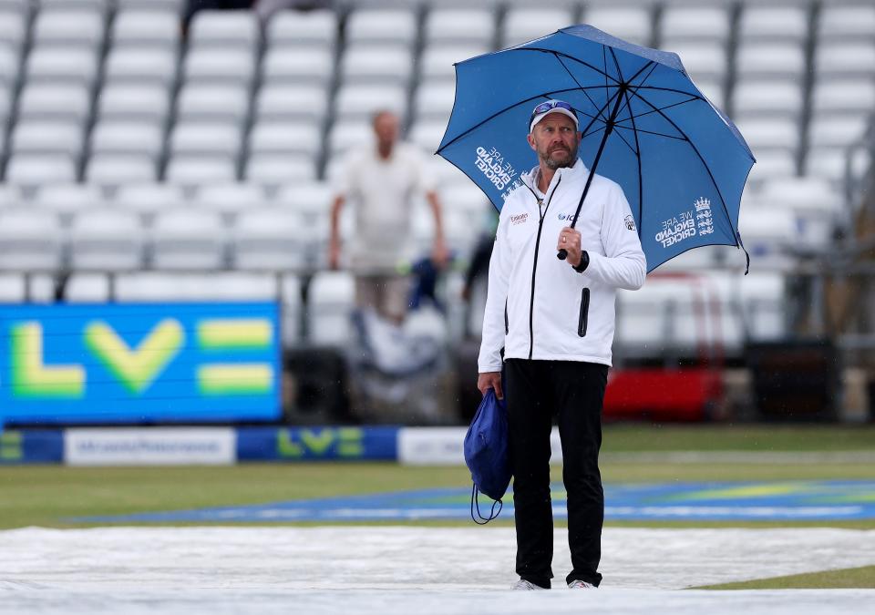 Umpire Mike Burns stands under an umbrella with all the covers on the ground at Headingley (Getty Images)