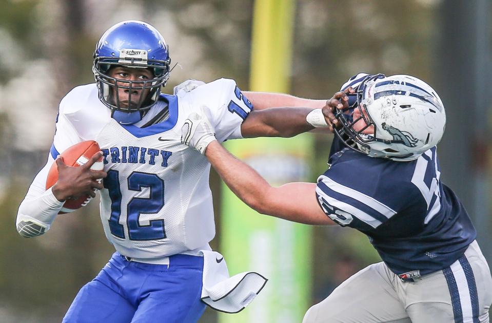 Trinity Christian quarterback Billy Cobb (12) stiff-arms American Heritage's Logan Wakefield (52) during the first half of the FHSAA high school Class 3A state football championship at the Citrus Bowl in Orlando, Fla., Saturday, Dec. 5, 2015. [Gary McCullough/For the Times-Union]