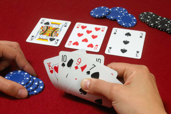 Poker hand with players hands against red baize