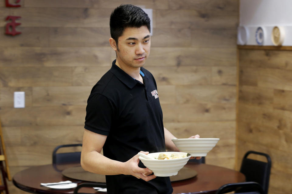 In this Feb. 13, 2020, photo, Owner Matthew Ma serves a meal at his restaurant inside Mekong Plaza in the Asian district in Mesa, Ariz. Arizona's freshly crowned Asian District was deep into organizing its night market when news broke that a case of the illness known as COVID-19 was confirmed at nearby Arizona State University. Xenophobic comments on social media and phone calls started almost immediately, according to Arizona Asian Chamber of Commerce CEO Vicente Reid. (AP Photo/Matt York)