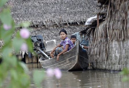 People sit on a boat near their home in a flooded village outside Zalun Township, Irrawaddy Delta, Myanmar, August 6, 2015. REUTERS/Soe Zeya Tun